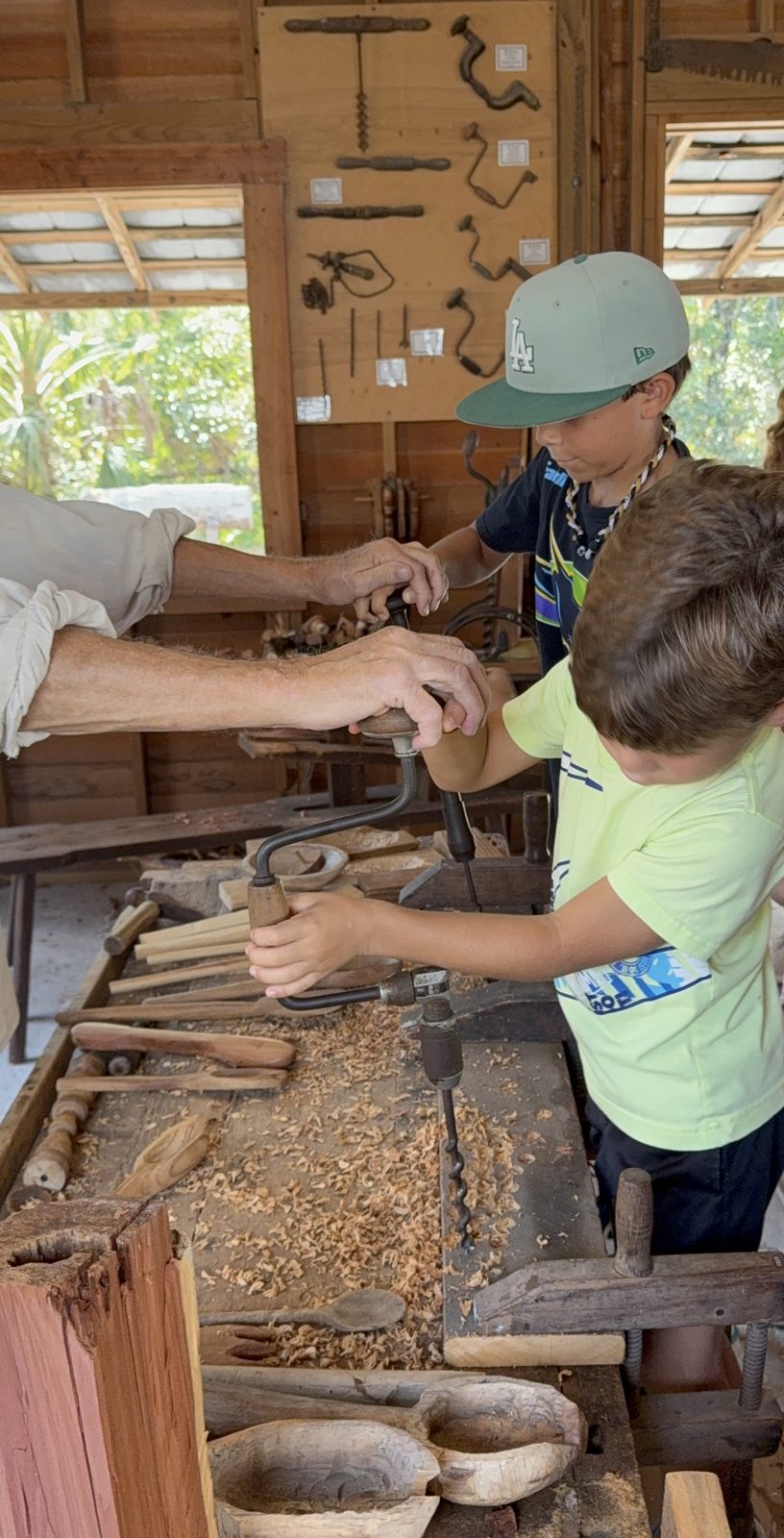 Seasons Schoolhouse students using hand-crank drills with a woodworking docent at a historic Florida village